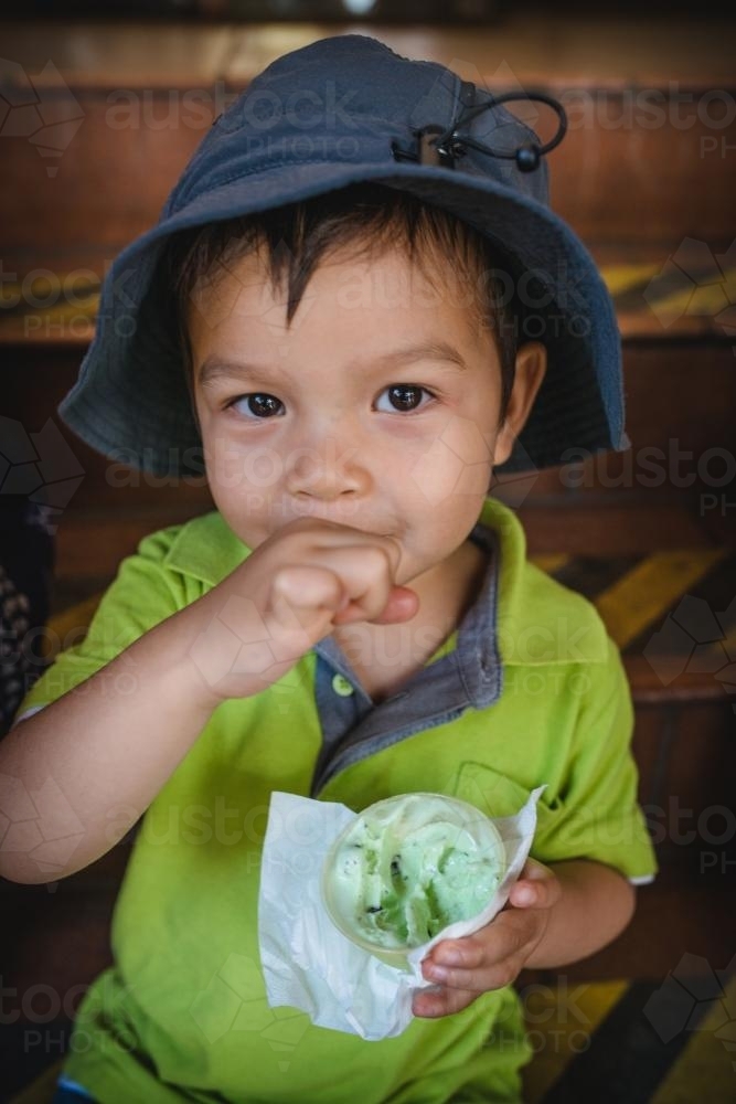 3 year old mixed race boy eating ice-cream on a warm summer day - Australian Stock Image