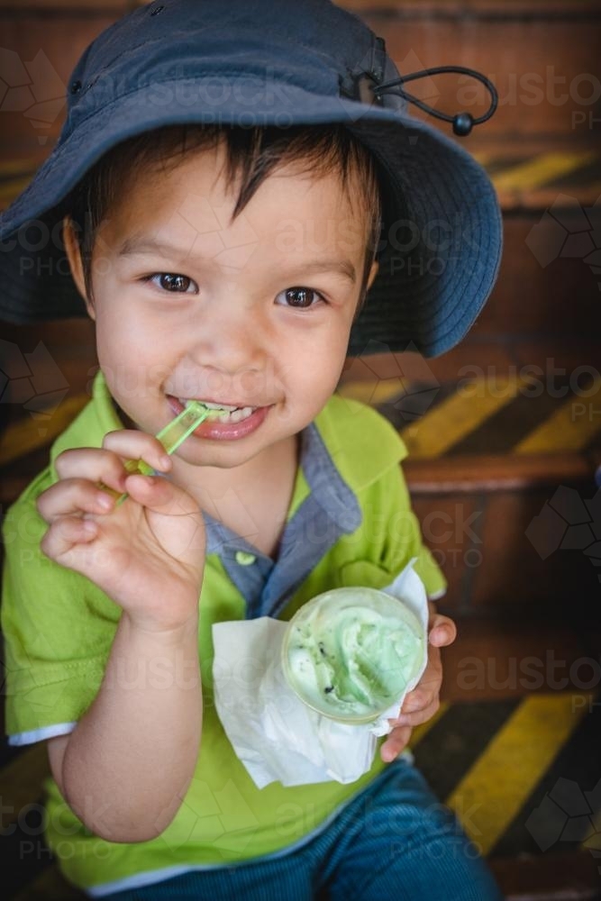 3 year old mixed race boy eating ice-cream on a warm summer day - Australian Stock Image