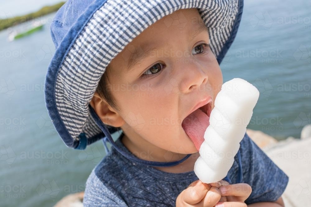 3 year old mixed race boy eating ice-cream on a warm summer day - Australian Stock Image