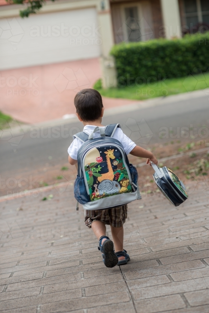 3 year old mixed race boy excitedly leaves home for his first day of school - Australian Stock Image
