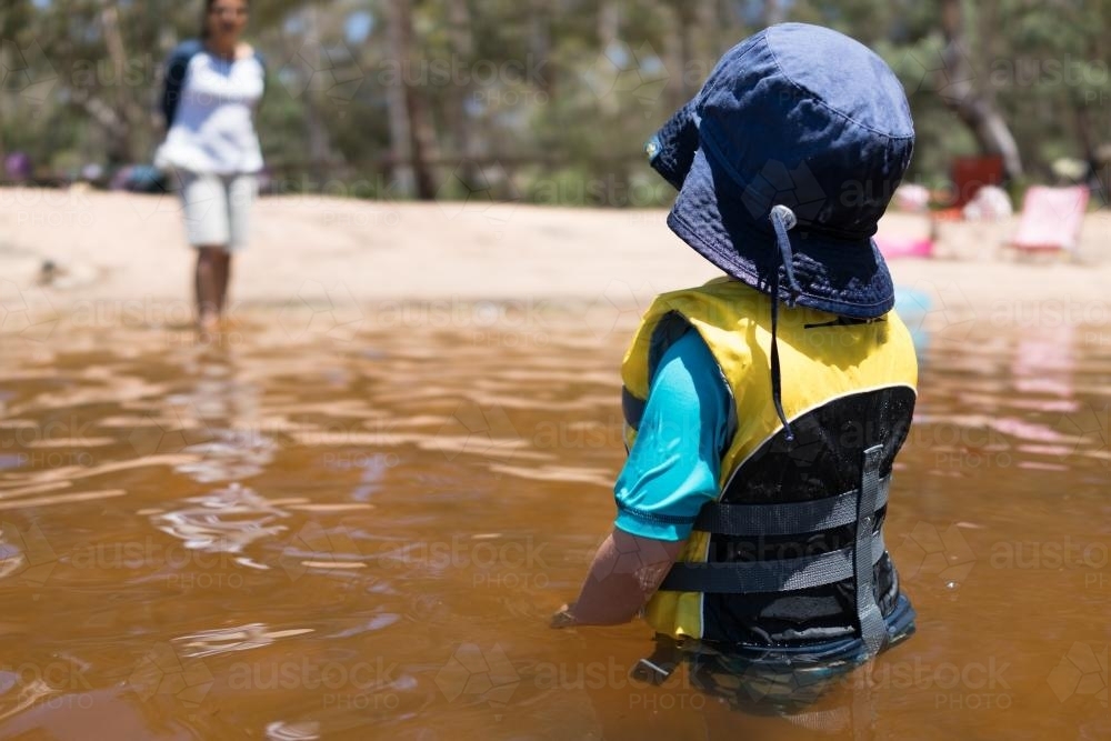 3 year old mixed race boy swims and plays in a river - Australian Stock Image