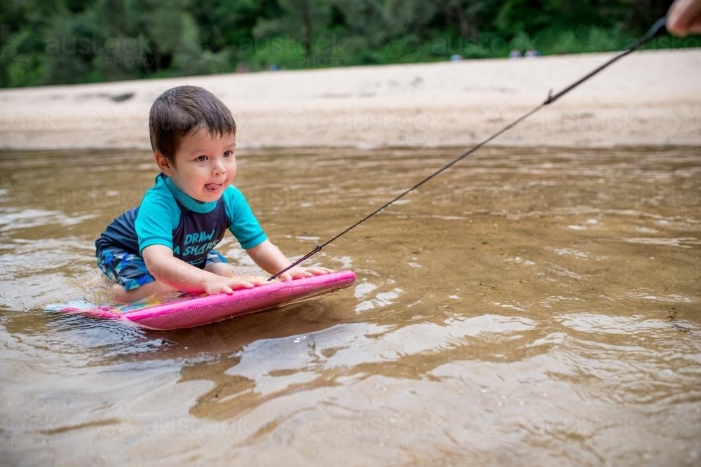 3 year old mixed race boy swims and plays in a river - Australian Stock Image
