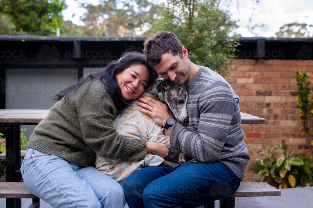 Image of 30something couple hugging their dog - Austockphoto