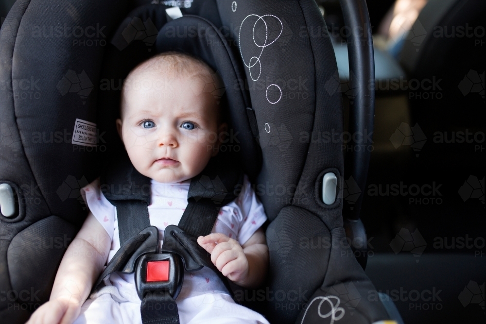 4 month old baby sitting in rear-facing car seat - Australian Stock Image