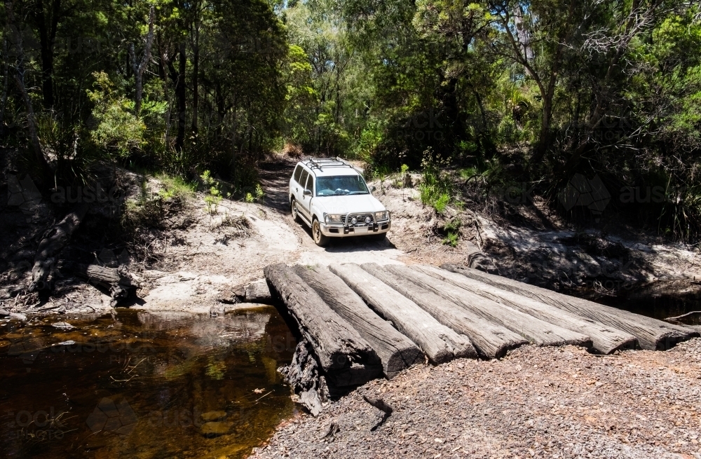 4 Wheel Drive crossing river over old tree logs - Australian Stock Image