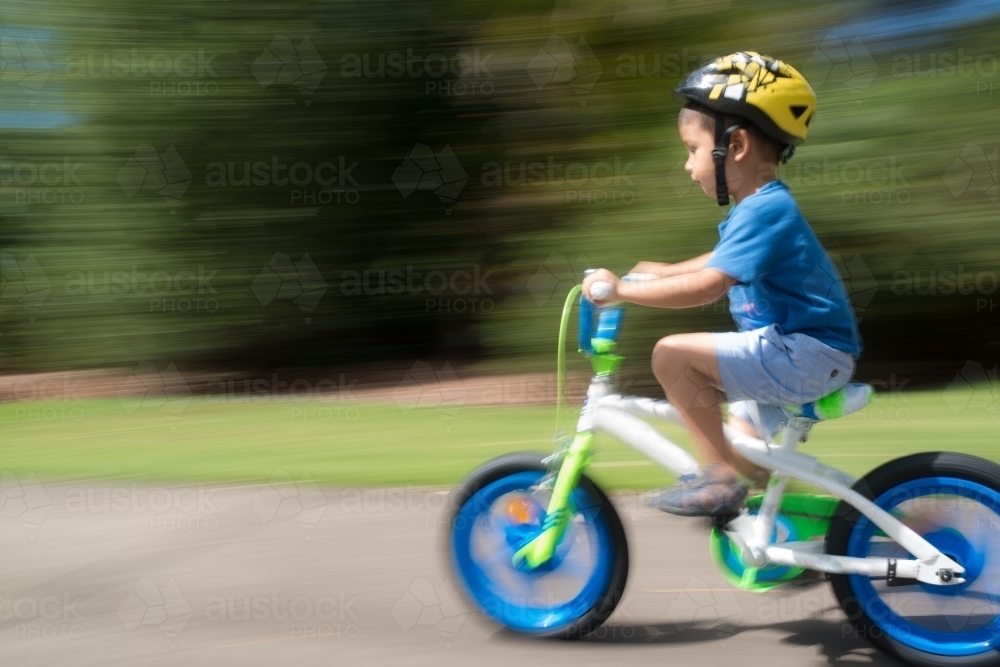 4 year old mixed race boy learns to ride his new bike for the first time. With motion blur - Australian Stock Image