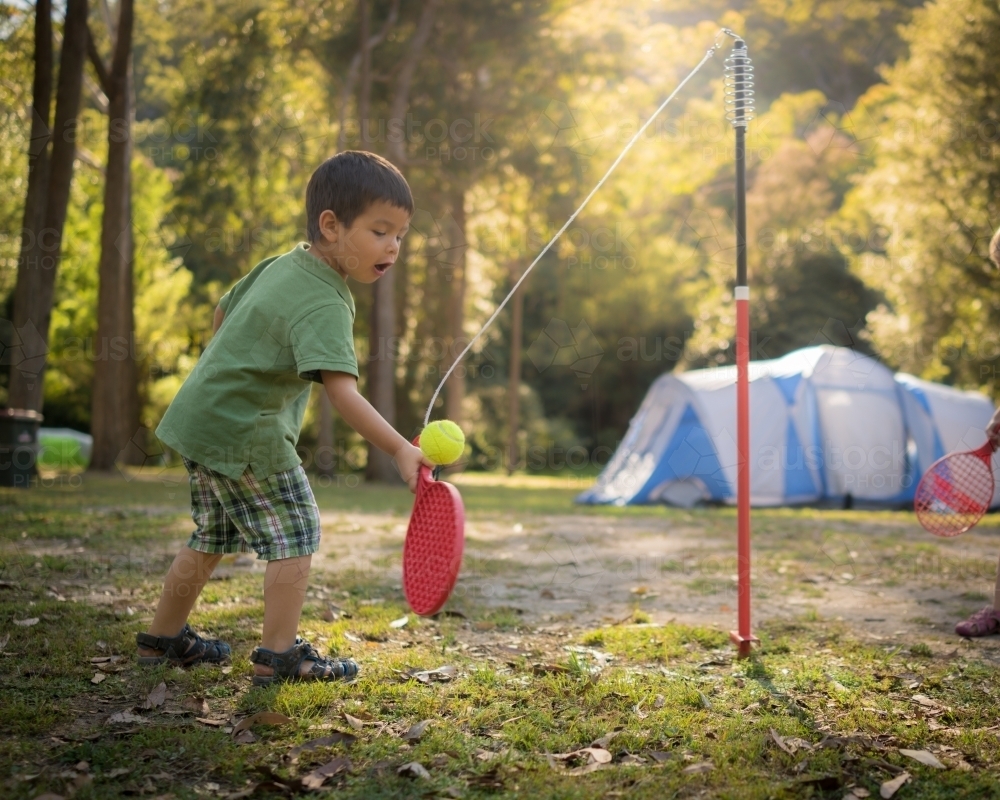 4 year old mixed race boy plays totem tennis on a camping trip - Australian Stock Image