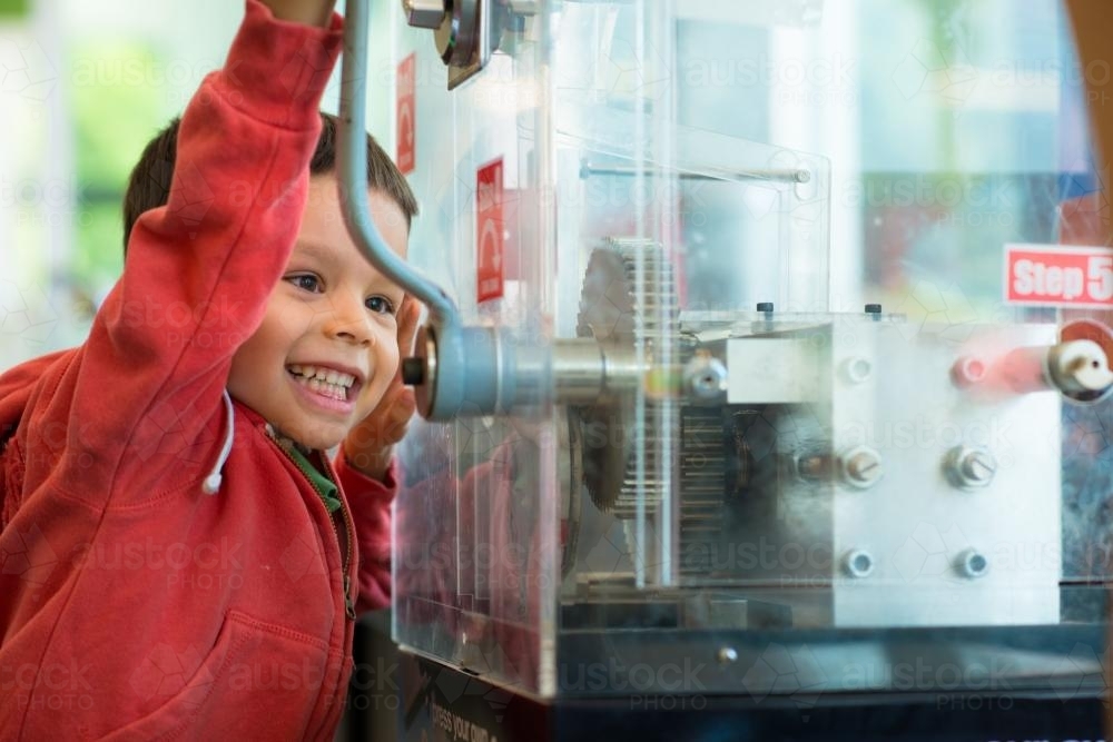 4 year old mixed race boy presses a souvenir penny at a local Sydney tourist attraction - Australian Stock Image
