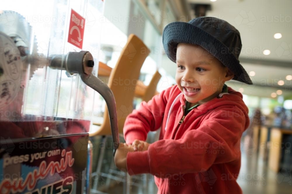 4 year old mixed race boy presses a souvenir penny at a local Sydney tourist attraction - Australian Stock Image