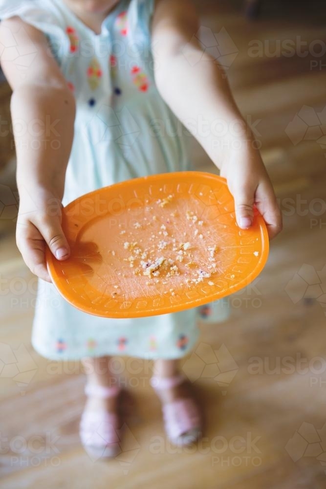 4 yo toddler showing empty plate to camera after finishing lunch or snack - Australian Stock Image