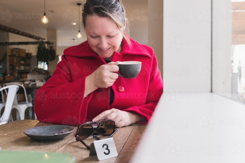 40 something woman enjoying a cup of coffee and some social media - Australian Stock Image