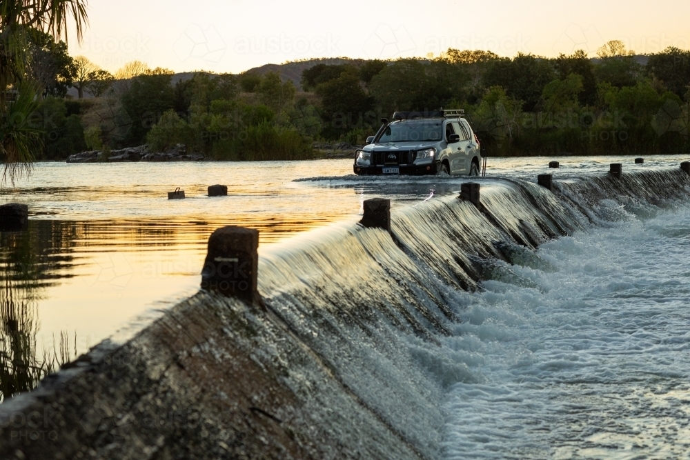 4wd car driving through flowing river crossing - Australian Stock Image
