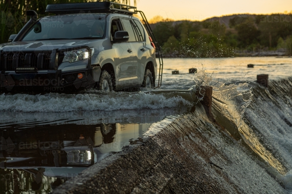 4wd car driving through flowing river crossing - Australian Stock Image