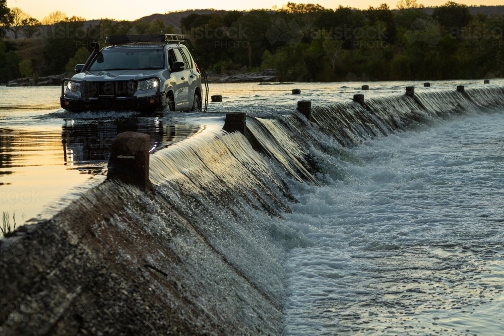 4wd car driving through flowing river crossing - Australian Stock Image