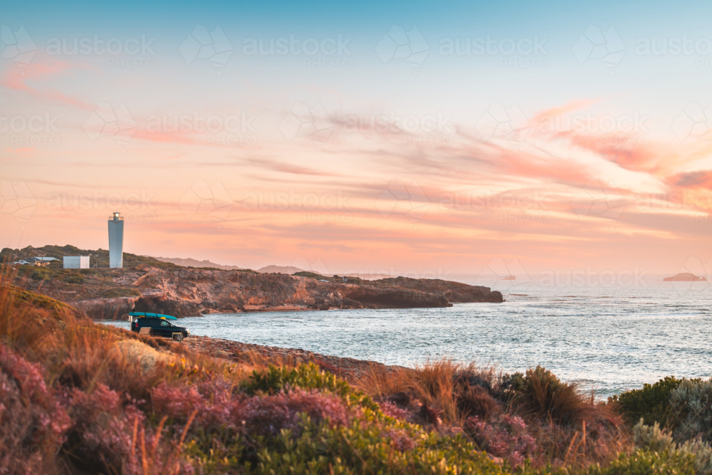 4WD car parked on rocky beach in Robe with driver enjoying the scenic sunset view with ocean - Australian Stock Image