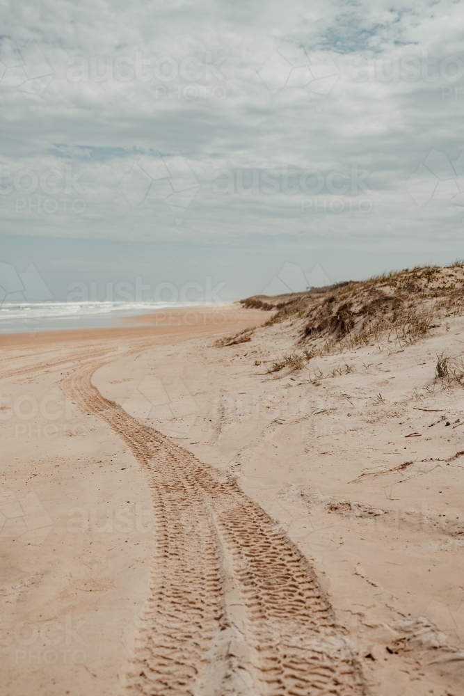 4WD tyre tracks leading down a deserted beach - Australian Stock Image