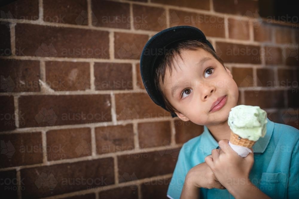 5 year old mixed race boy eating ice-cream on a warm summer day - Australian Stock Image