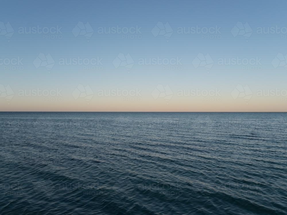 50:50 split calm blue sea and blue sky at dusk - Australian Stock Image