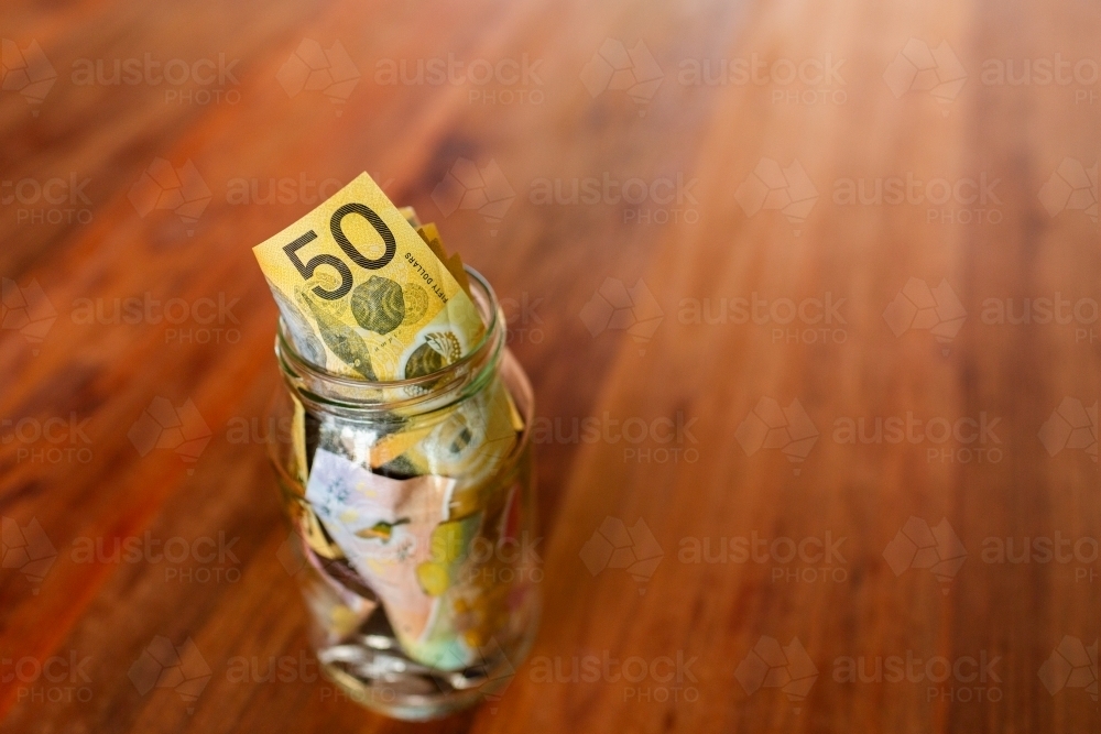 50 dollar australian notes and other cash in jar on wooden table - Australian Stock Image