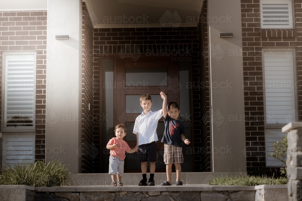6 year old mixed race boy with his brothers leaves home for his first day of school - Australian Stock Image