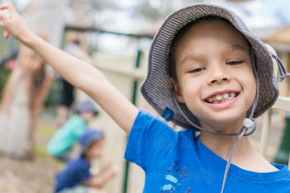 7 year old mixed race boy smiling and wearing a hat outside - Australian Stock Image