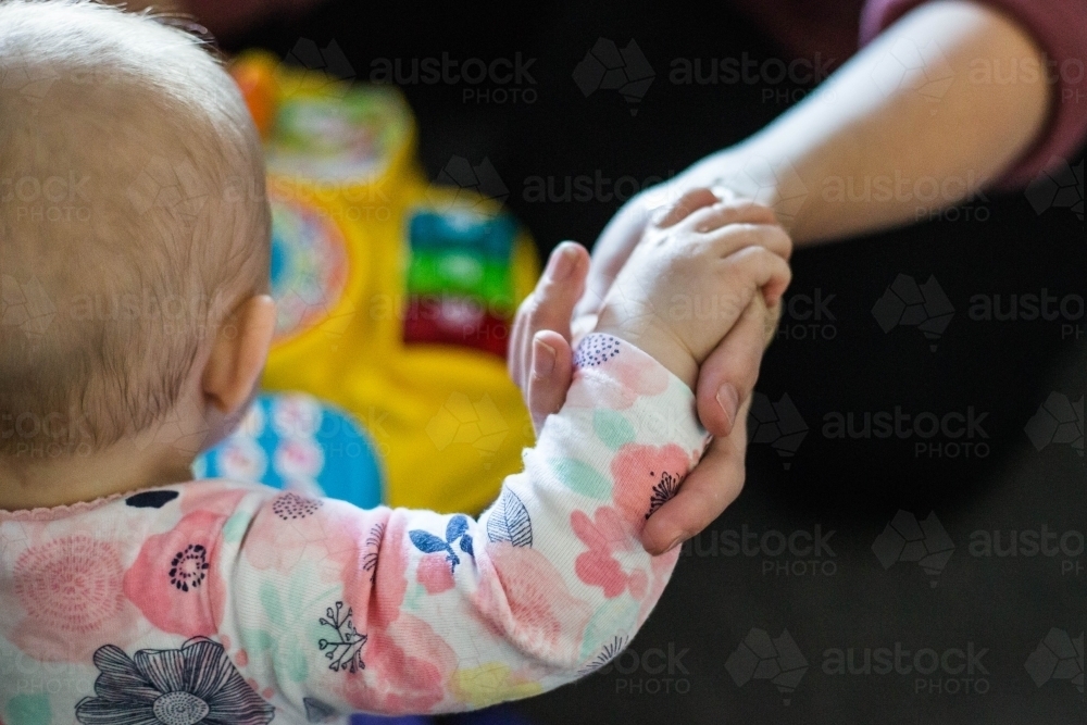 Baby and mum holding hands - Australian Stock Image