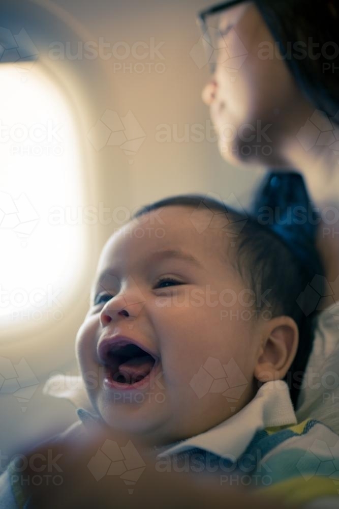 9 month old mixed race baby boy travels with his mother on a commercial aeroplane flight - Australian Stock Image