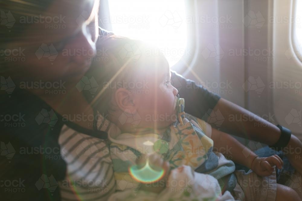 9 month old mixed race baby boy travels with his mother on a commercial aeroplane flight - Australian Stock Image