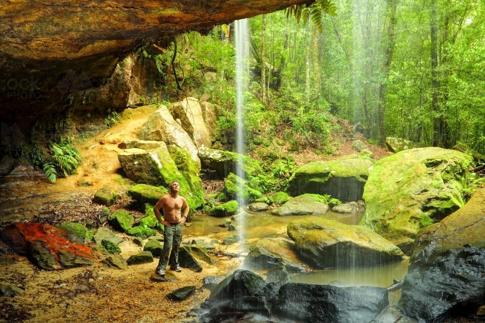 A bare-chested man in his mid forties admires the waterfall at Glow-Worm Nook Falls - Australian Stock Image