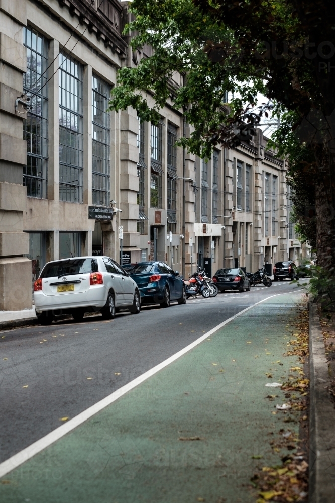 A bicycle lane and a warehouse conversion block under the train tracks in North Sydney with cars - Australian Stock Image