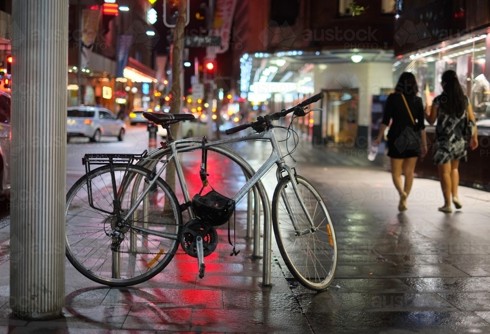 a bike parked in the city on a rainy night - Australian Stock Image