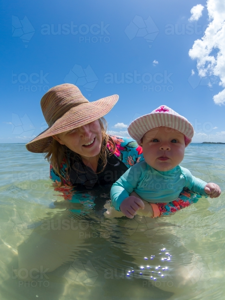 A blonde mum in her late thirties with baby playing at beach. - Australian Stock Image
