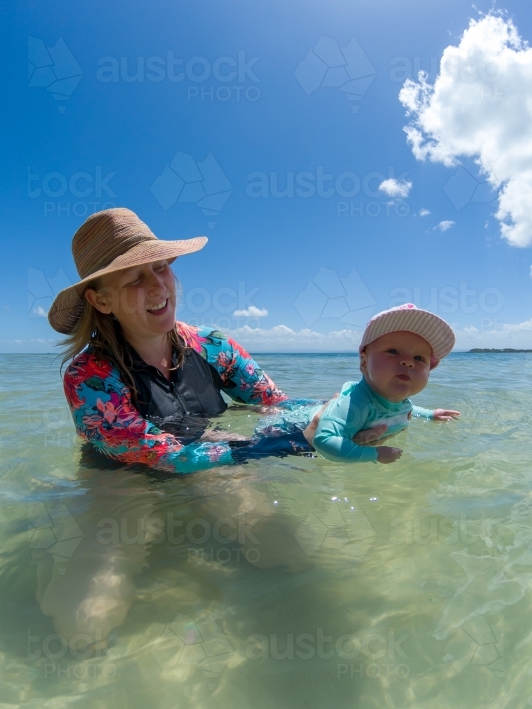 A blonde mum in her late thirties with baby playing at beach. - Australian Stock Image