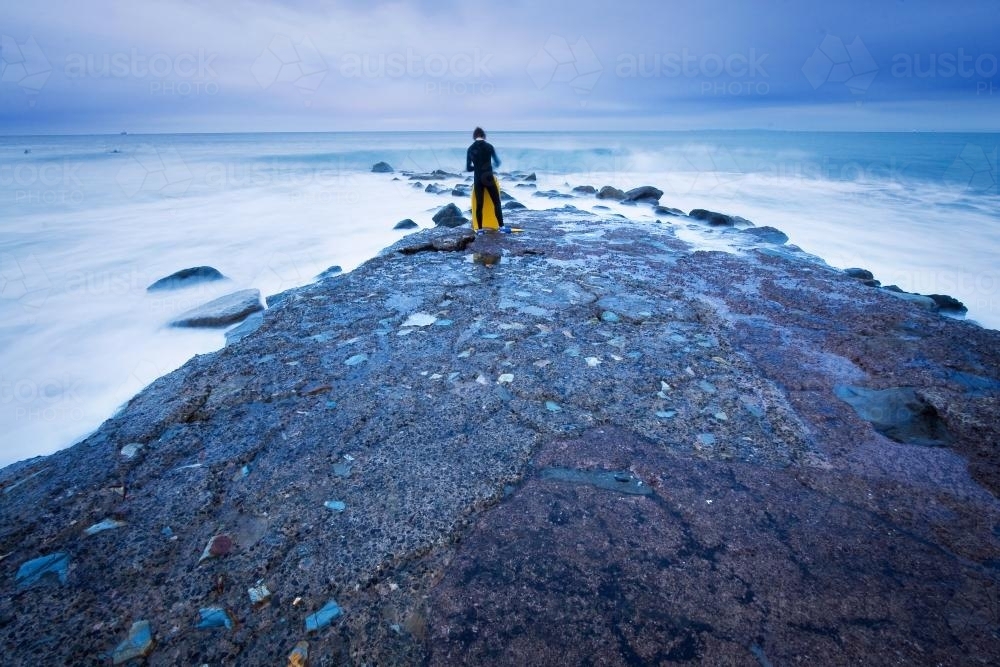 A boogie board rider walks out into the rough seas - Australian Stock Image