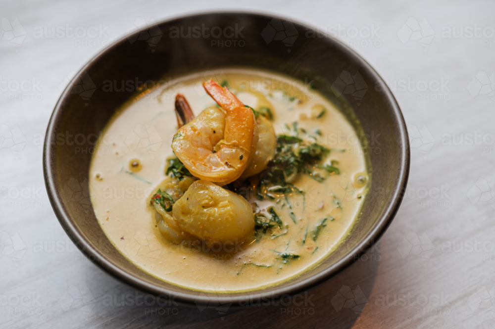 A bowl of flavourful Asian seafood yellow curry with prawn and greens - Australian Stock Image