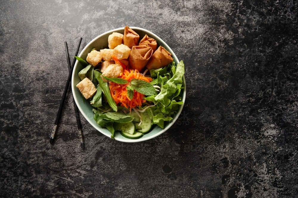 a bowl of green salad with fried tofu and lumpias - Australian Stock Image