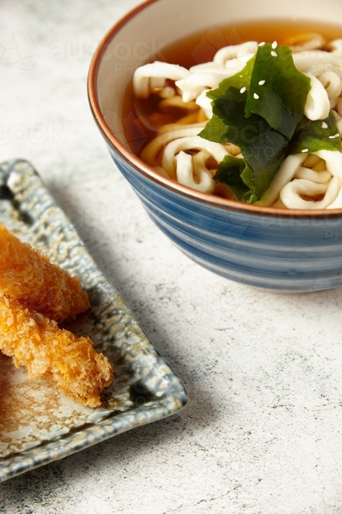 A bowl of Japanese udon noodles with fried side dish - Australian Stock Image