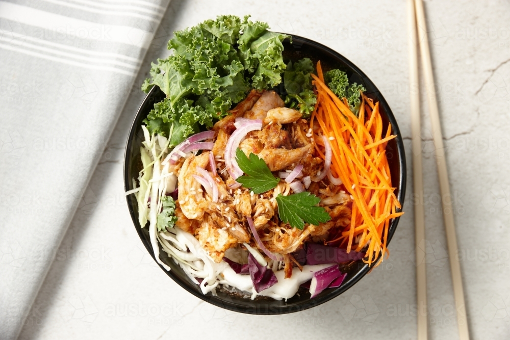 A bowl of thai chicken salad with chopsticks and kitchen towel on the white surface - Australian Stock Image