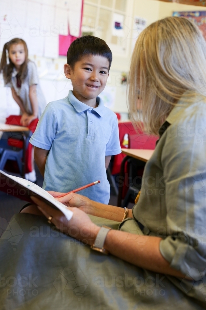 A boy in school uniform talking to his teacher - Australian Stock Image