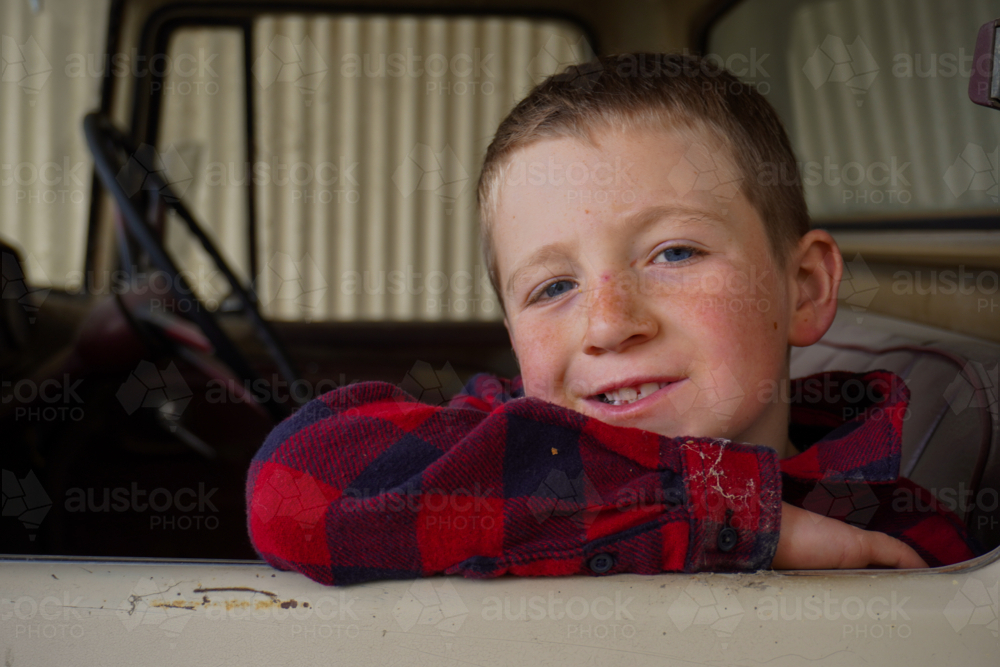 A boy resting on an elbow on the windowsill of an old truck - Australian Stock Image