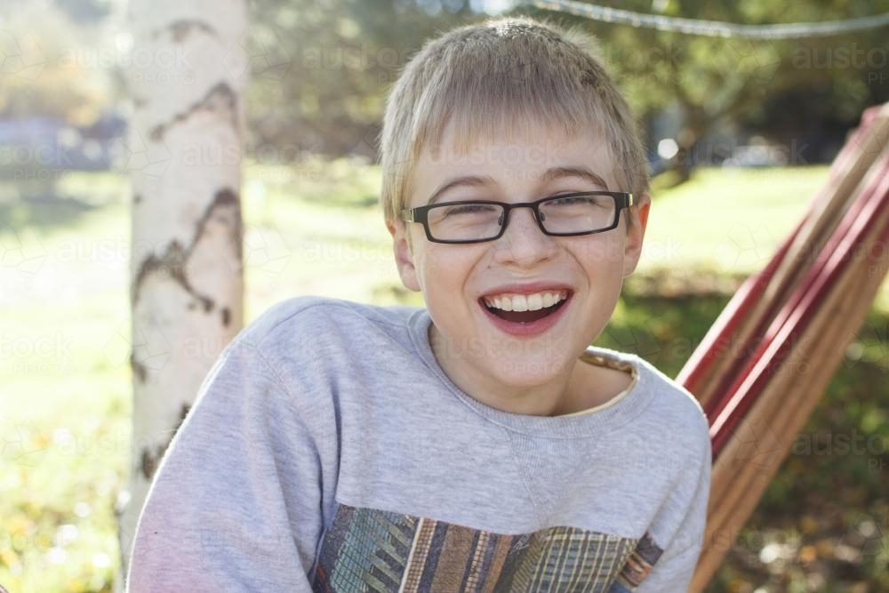 A boy sitting outside, smiling - Australian Stock Image