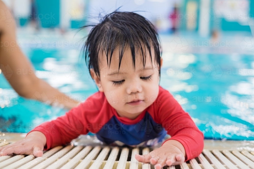 A boy toddler crawling by the pool - Australian Stock Image