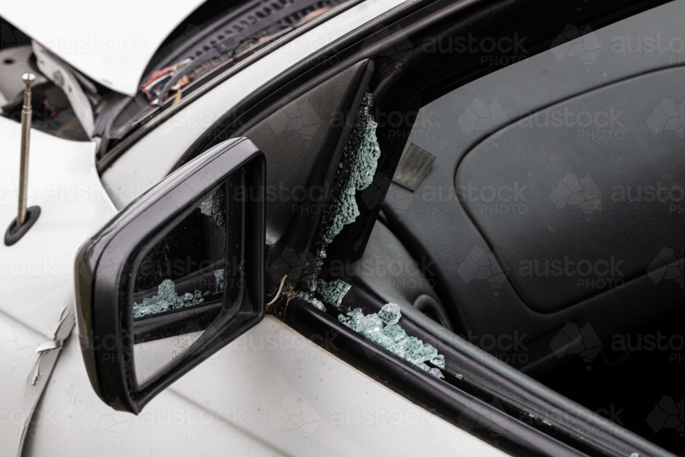 A broken car window and side mirror after a bad car crash accident in a white car - Australian Stock Image