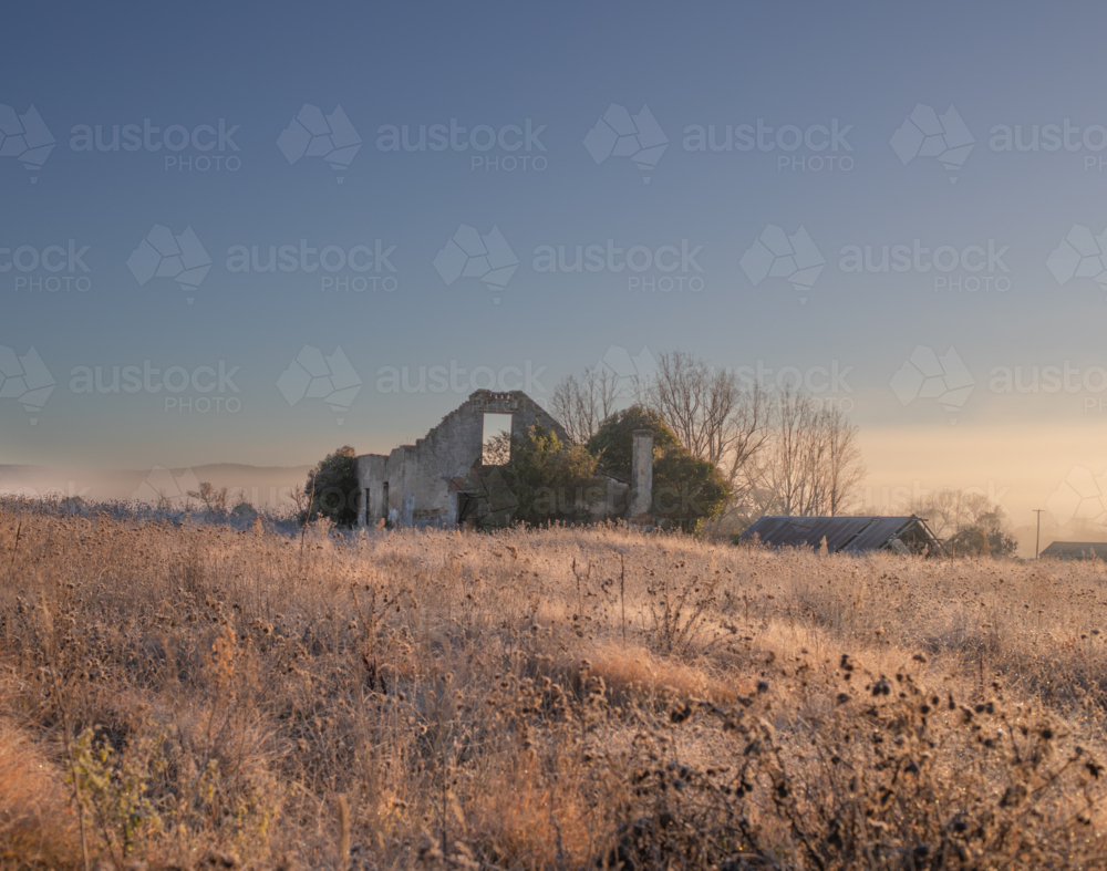 A broken down building in a frosty field under a blue sky - Australian Stock Image
