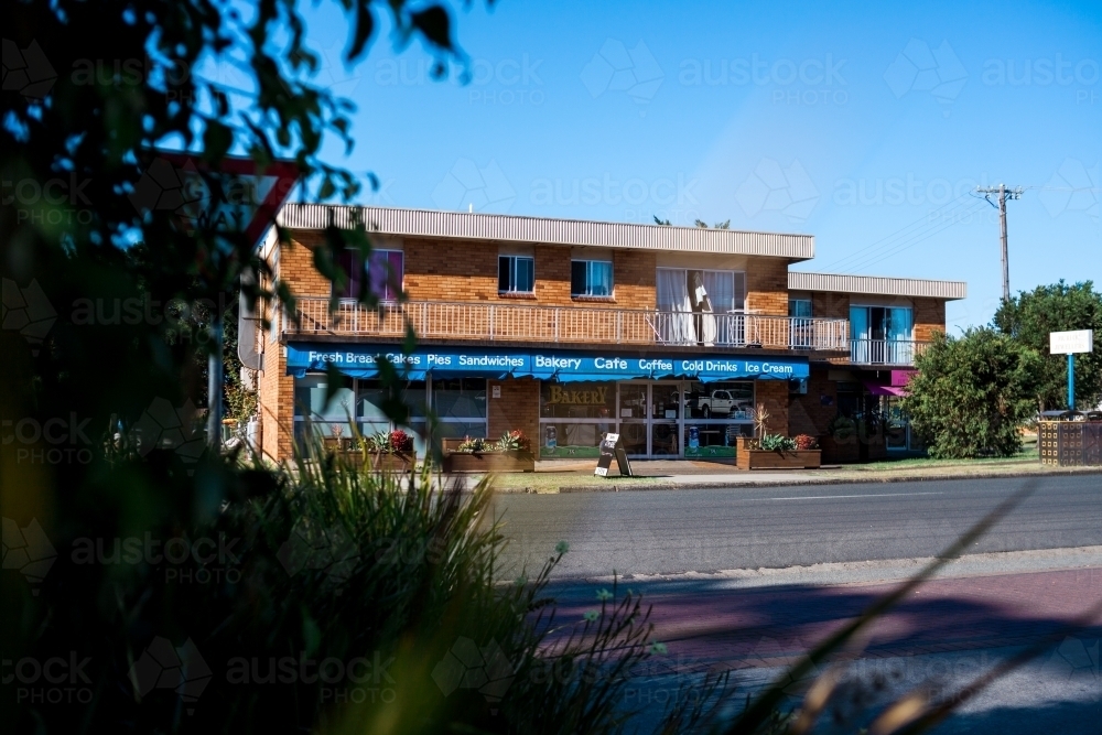 A building across a road with blue signage advertising a bakery in a small regional town - Australian Stock Image