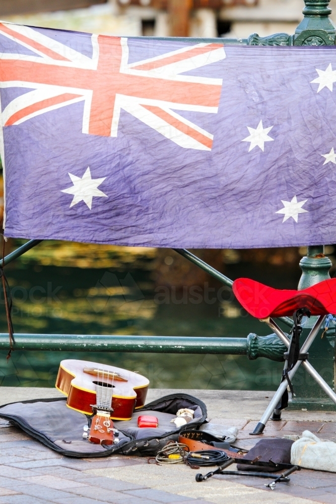 A busker's guitar and stool in front of the Australian Flag - Australian Stock Image