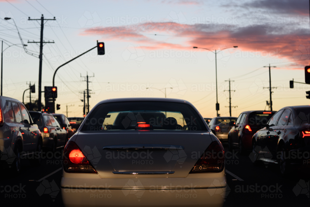 A busy street during evening rush hour with a background of car taillights and a sunset sky - Australian Stock Image