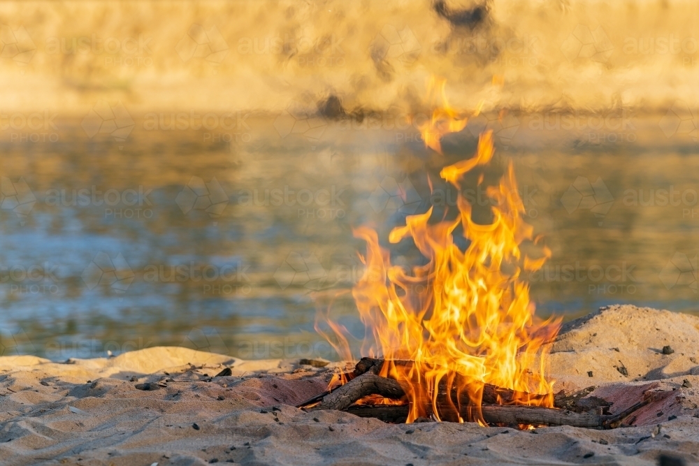 A camp fire burning on a river bank - Australian Stock Image