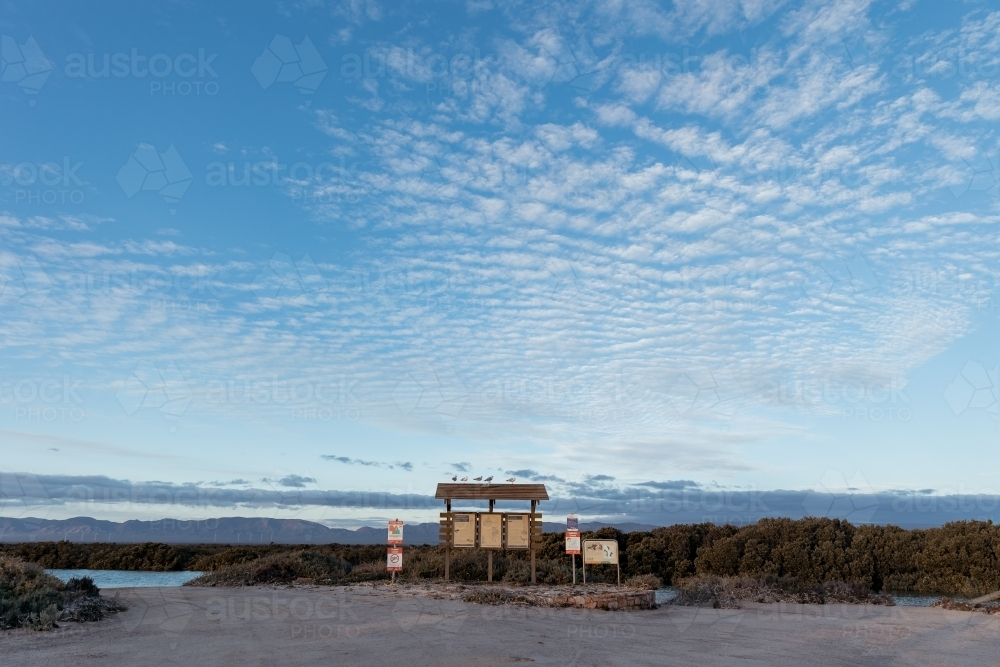 A campground sign board on flat sandy ground surrounded by blue sky - Australian Stock Image