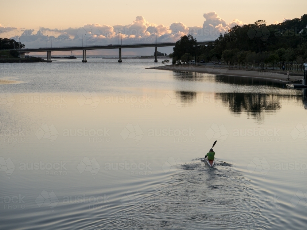 A canoe paddling down a river in the early morning - Australian Stock Image